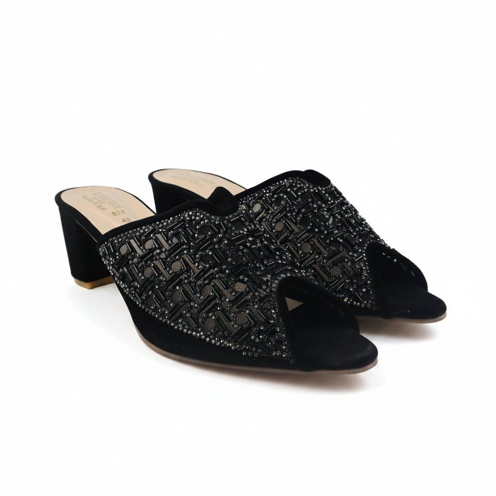 A pair of black open-toe mule heels with a textured, beaded chevron pattern across the straps, set against a plain white background.