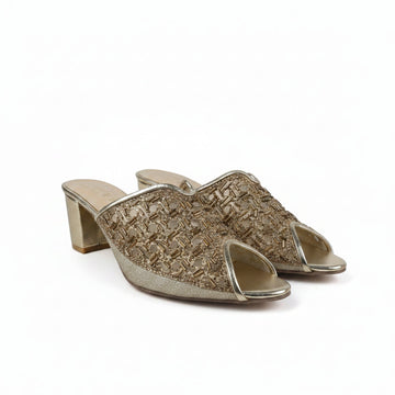 A pair of women's heeled mule sandals with a textured metallic gold woven upper and a chunky block heel, shown on a light gray fabric background.