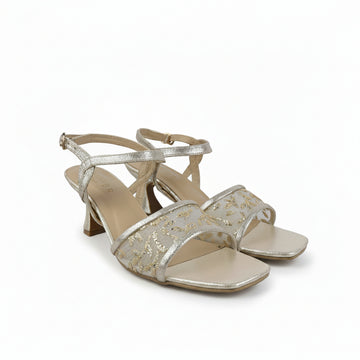 A pair of women's heeled sandals in a metallic champagne gold color, featuring an open toe, a square toe cap, and a thin ankle strap with a buckle closure. The straps are embellished with a textured, glittery pattern, and the insole is a light beige nude color.