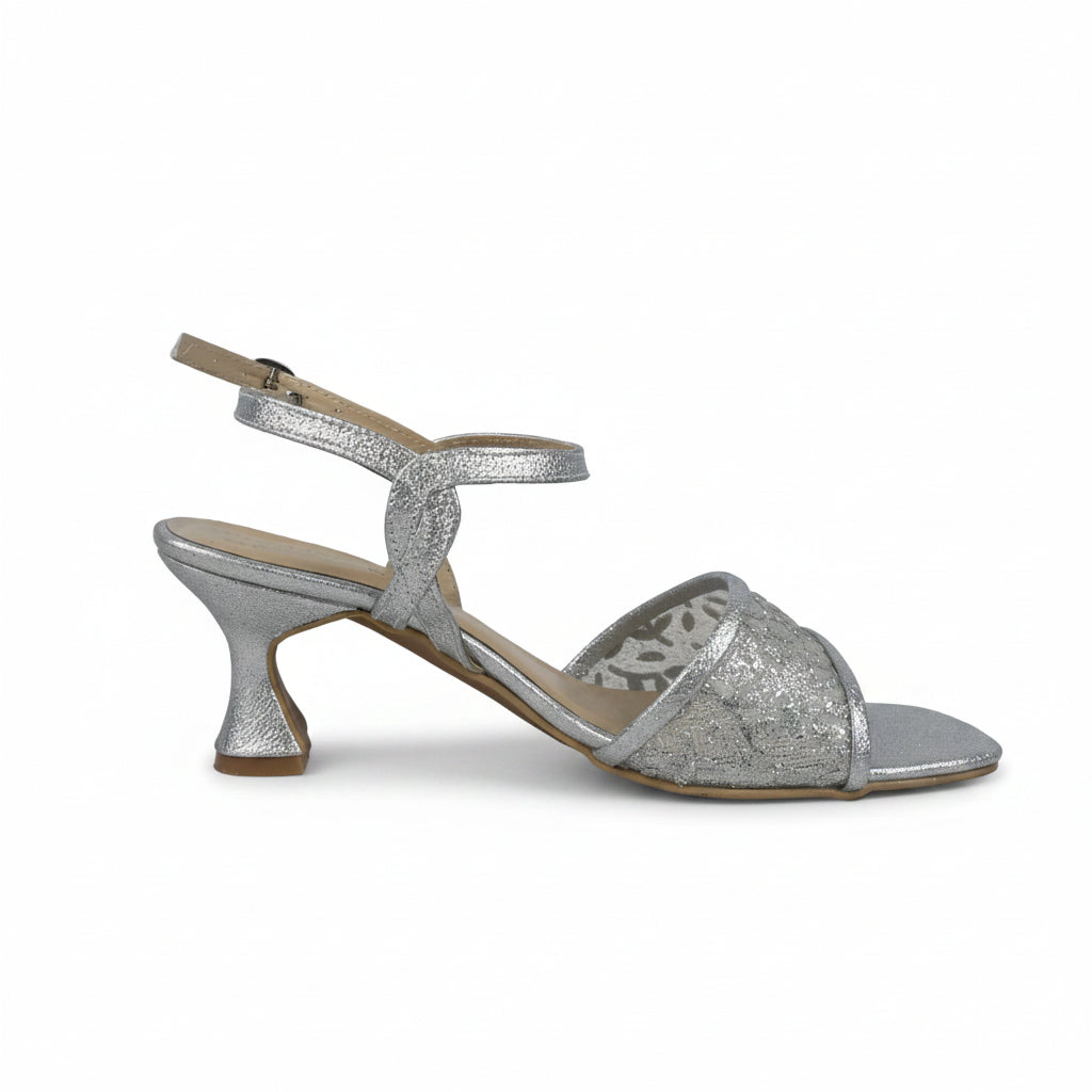 A single silver glitter heeled sandal with an ankle strap and open toe, shown from the side against a light gray textured background.