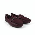 A pair of women's burgundy leather driving loafers with a small silver-tone metal logo charm on the strap, displayed on a light gray studio background.