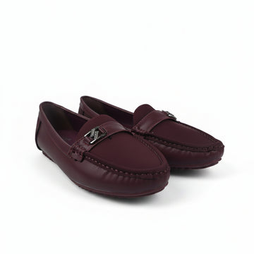 A pair of women's burgundy leather driving loafers with a small silver-tone metal logo charm on the strap, displayed on a light gray studio background.