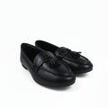A pair of black leather tassel loafers photographed on a white studio background.
