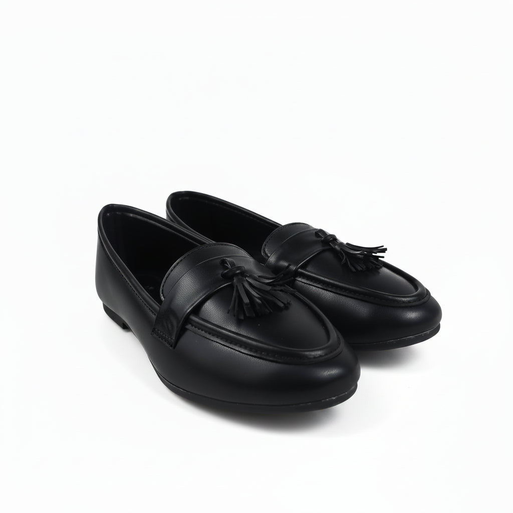 A pair of black leather tassel loafers photographed on a white studio background.