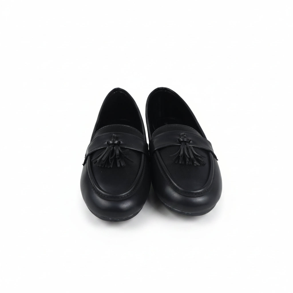 A pair of black leather tassel loafers photographed on a white studio background.