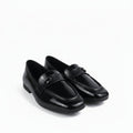 A pair of glossy black patent leather loafers with a small silver-tone horsebit detail on the strap, displayed on a white studio background.