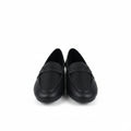 A pair of black slip-on loafers with perforated detailing on the upper, displayed on a white surface next to an open brown cardboard shoebox.