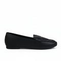 A single black leather slip-on loafer shown in profile against a light gray textured studio background.