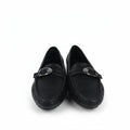 A pair of black leather loafers with a silver-tone metal horsebit detail across the vamp, displayed on a white surface with a red and black shoebox partially visible on the right.