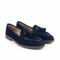 A pair of navy blue suede tassel loafers with black trim and tan soles, displayed on a white studio background.