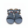 A pair of Metylan blue woven sandals with adjustable straps, shown next to a red Metylan shoebox on a white background.