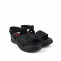 A pair of black woven-look slide sandals with adjustable ankle straps and bow details, photographed on a light gray studio background.