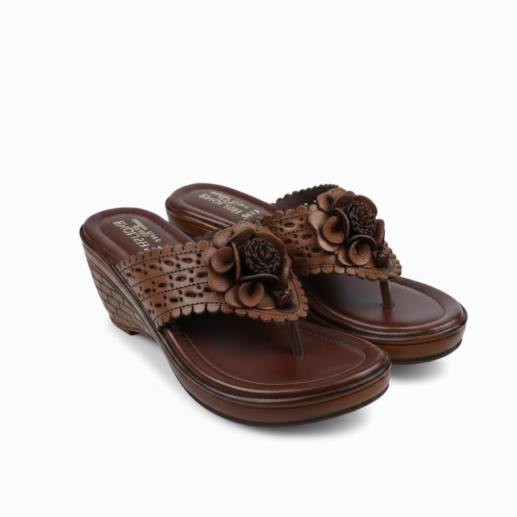 A pair of black wedge sandals with textured straps and 3D floral embellishments, shown on a plain white background.