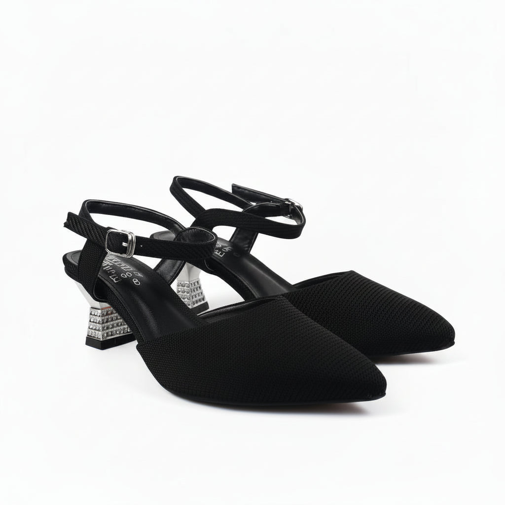 A pair of black pointed-toe slingback pumps with ankle straps and chunky block heels, photographed on a white studio background.