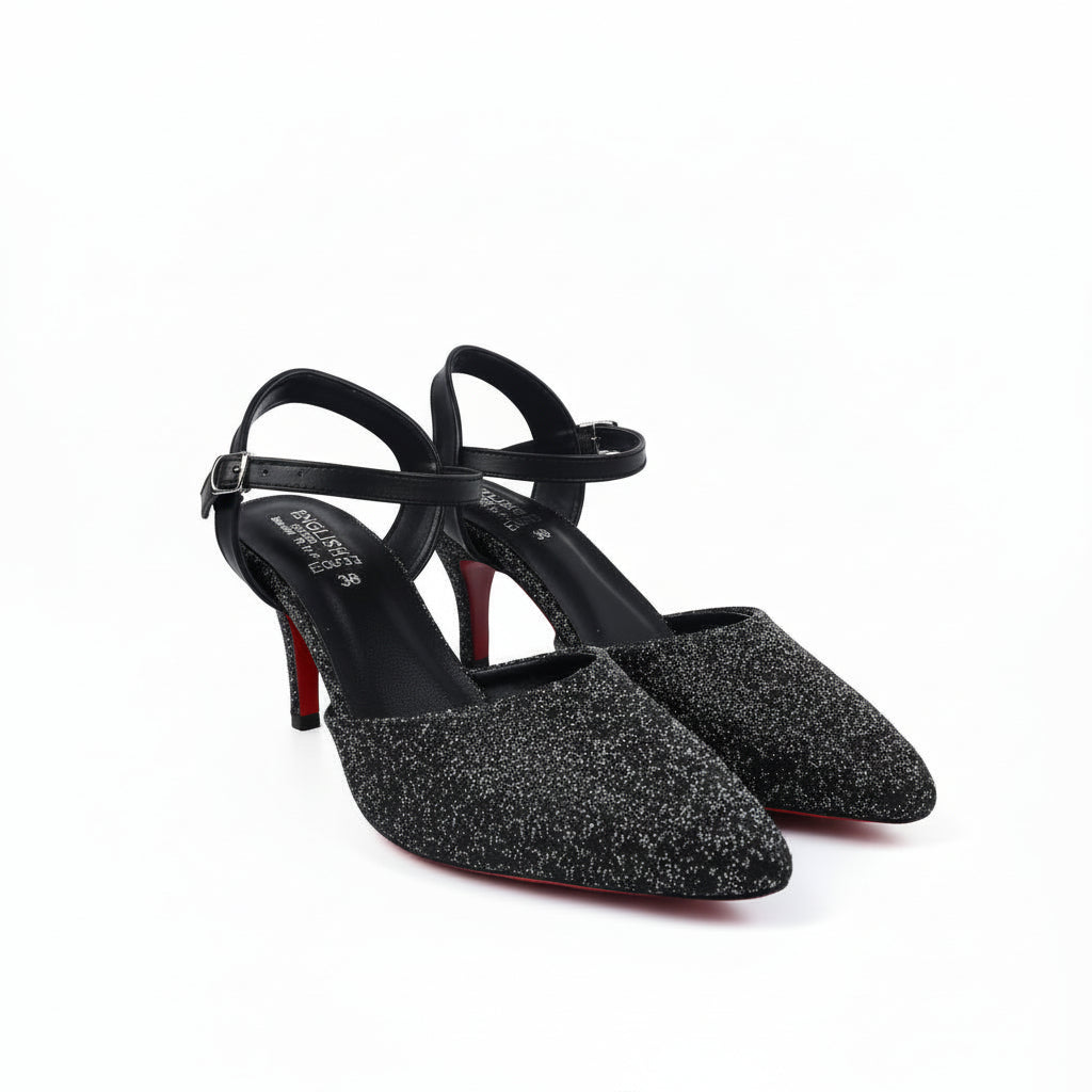 A pair of pointed-toe high heels covered in gold glitter, featuring gold ankle straps and red low-profile heels, photographed on a white studio background.