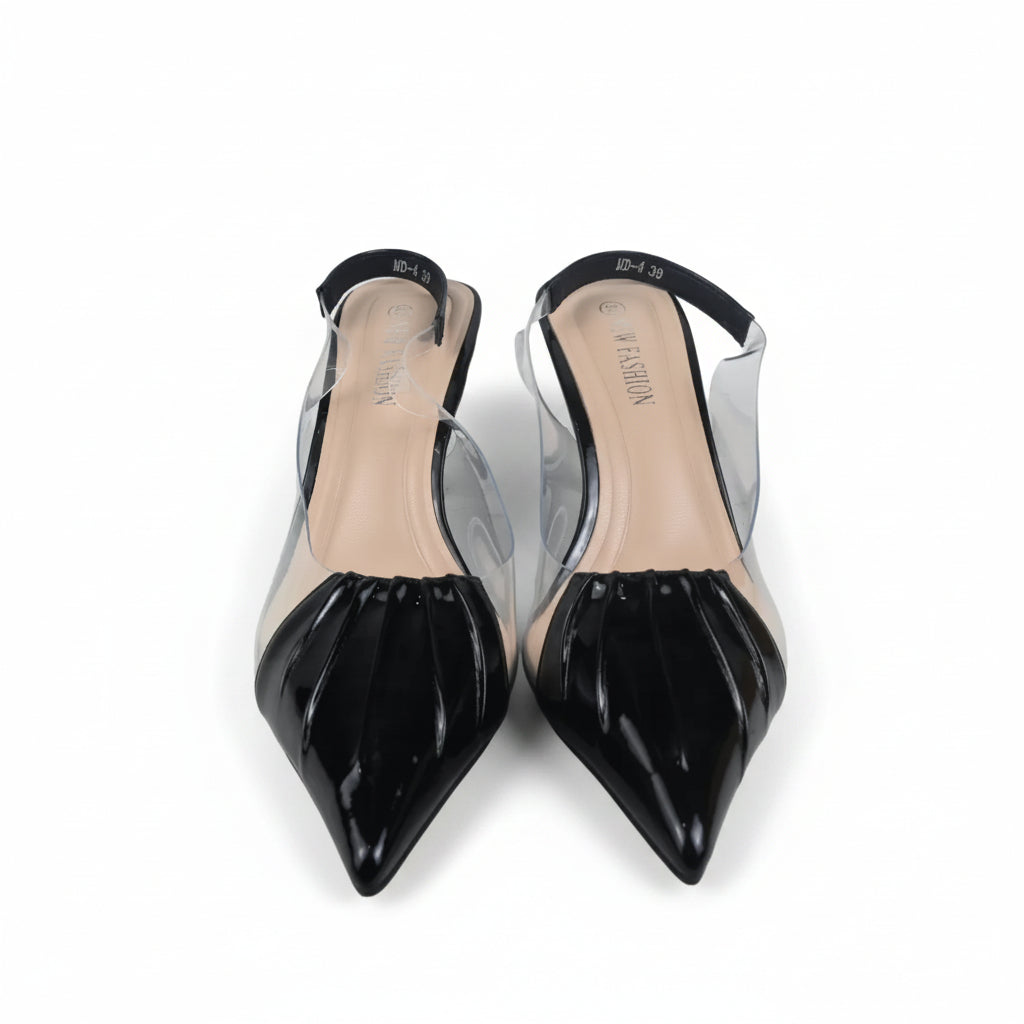 A pair of pointed-toe slingback heels with glossy black patent leather caps and clear transparent straps, shown on a light gray surface with a partial orange box visible on the right.