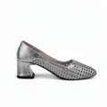 A single metallic silver pump shoe with a textured, woven pattern on the upper and a block heel, shown against a light gray fabric backdrop.