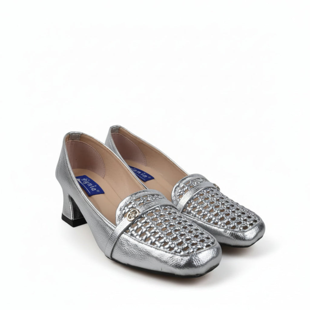 A pair of metallic silver kitten heels with woven textured detailing across the vamp, displayed on a light gray fabric backdrop.