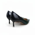 A pair of women's pointed-toe high heels in glossy black patent leather with a dark green side panel and clear protective caps on the heels, shown against a white studio background.