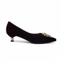 A single dark burgundy velvet pointed-toe pump with a gold-tone decorative buckle and a small gold-tone heel accent, shown against a plain light gray background.