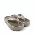 A pair of beige platform flip-flop sandals with a textured grip sole, displayed on a white fabric backdrop.