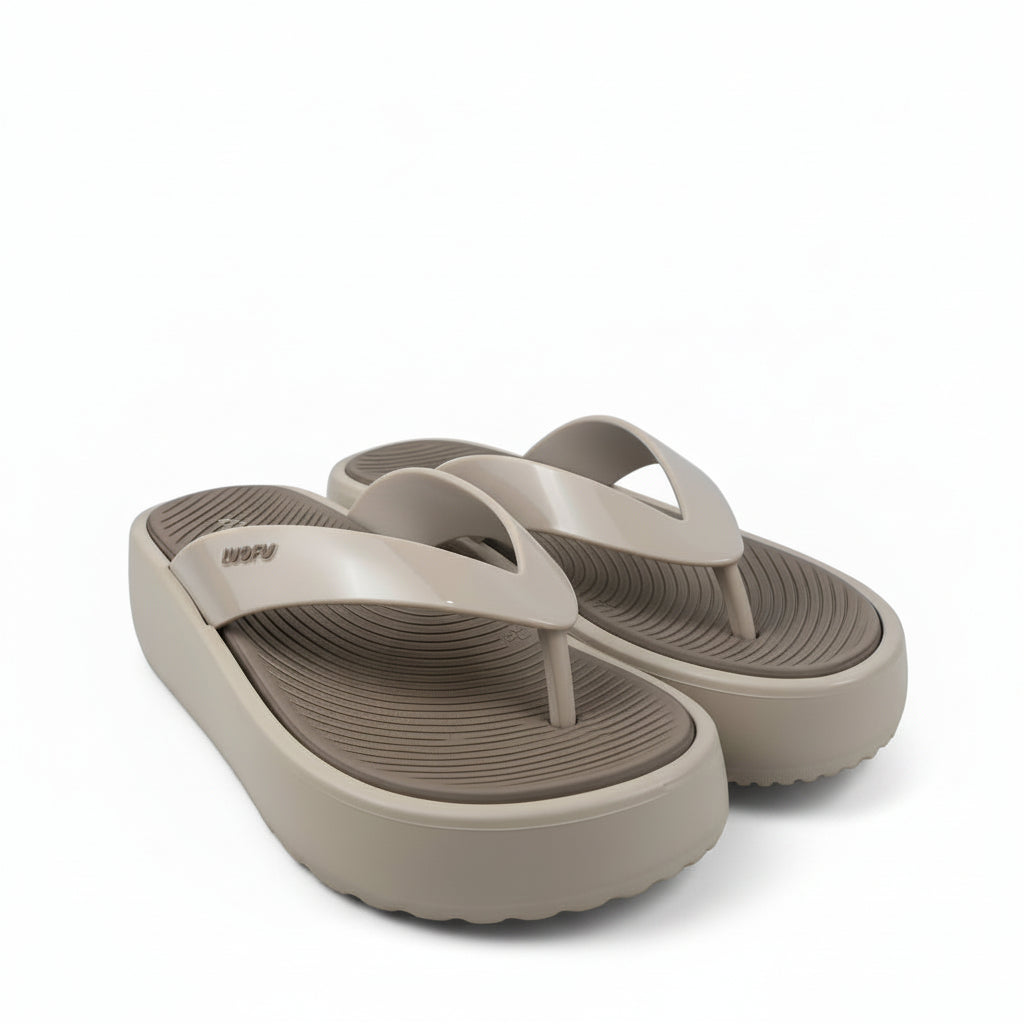 A pair of beige platform flip-flop sandals with a textured grip sole, displayed on a white fabric backdrop.