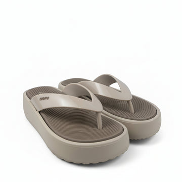 A pair of beige platform flip-flop sandals with a textured grip sole, displayed on a white fabric backdrop.