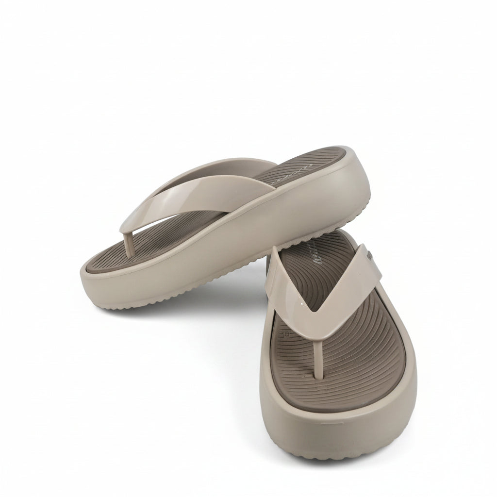 A pair of beige platform flip-flop sandals with a textured grip sole, displayed on a white fabric backdrop.