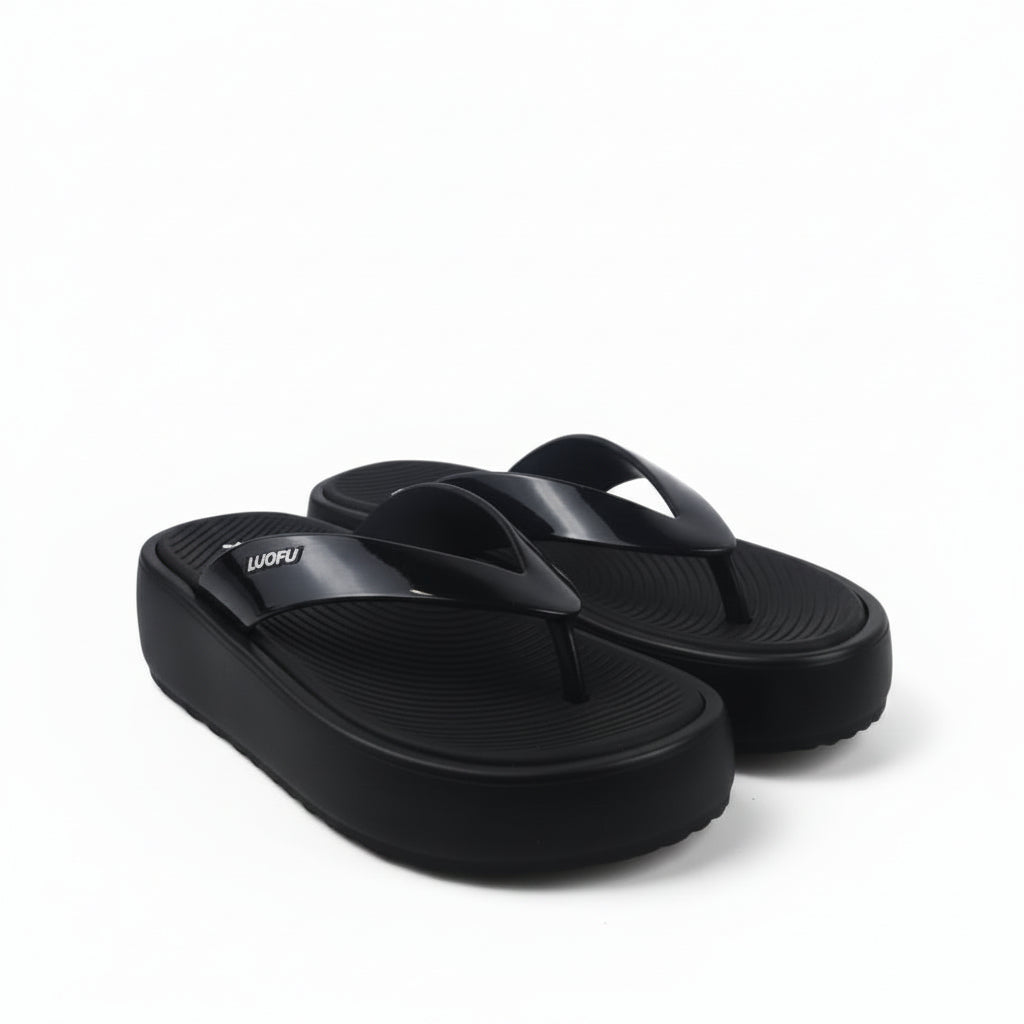 A pair of black platform flip-flops with thick straps, photographed on a white studio background with a black power cord visible in the lower left.