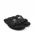 A pair of black leather slide sandals with double straps and silver-tone buckle details, photographed on a white fabric backdrop.