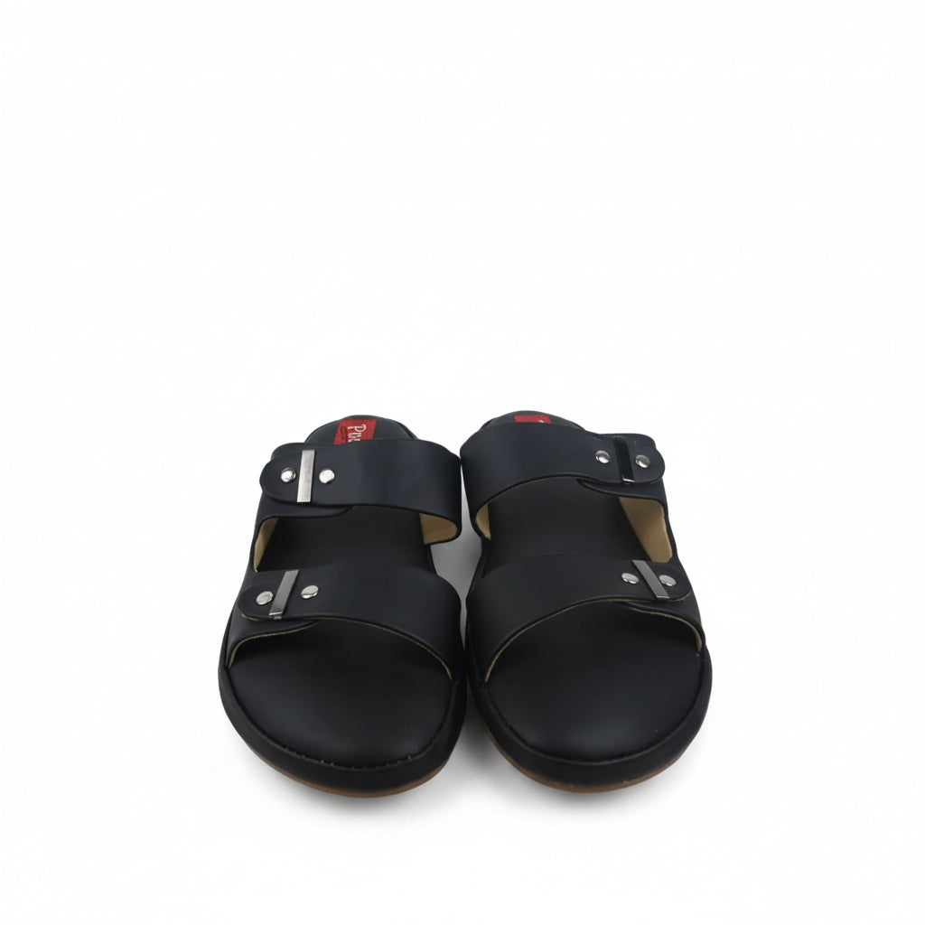 A pair of black leather slide sandals with double straps and silver metal rivets, shown next to a purple shoebox on a white background.