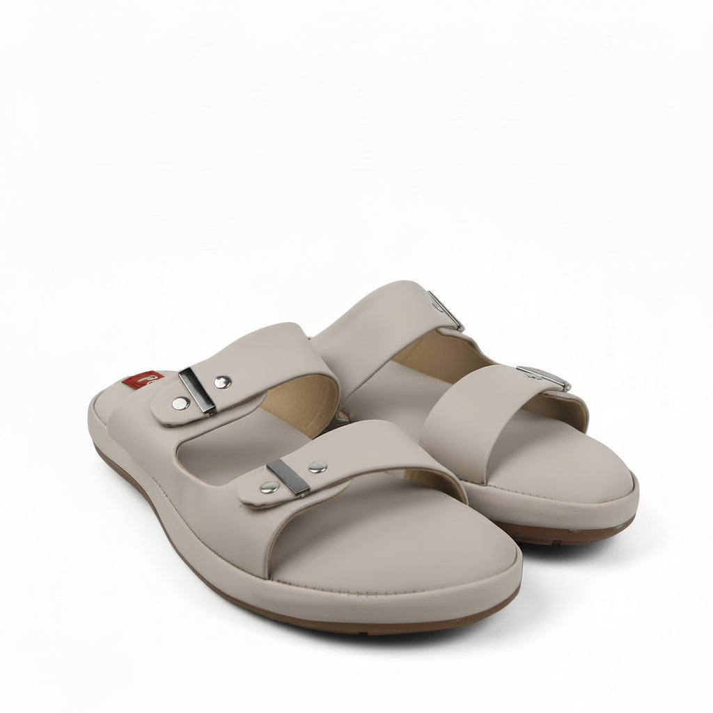 A pair of beige double-strap slide sandals with metal buckle closures, photographed on a white studio background.
