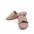 A pair of women's slide sandals in a dusty pink color, displayed on a light gray background with a purple shoebox partially visible on the right.