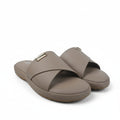 A pair of taupe leather slide sandals with crossed straps and a small gold-tone metal brand plaque on the top strap, displayed on a white studio sweep.