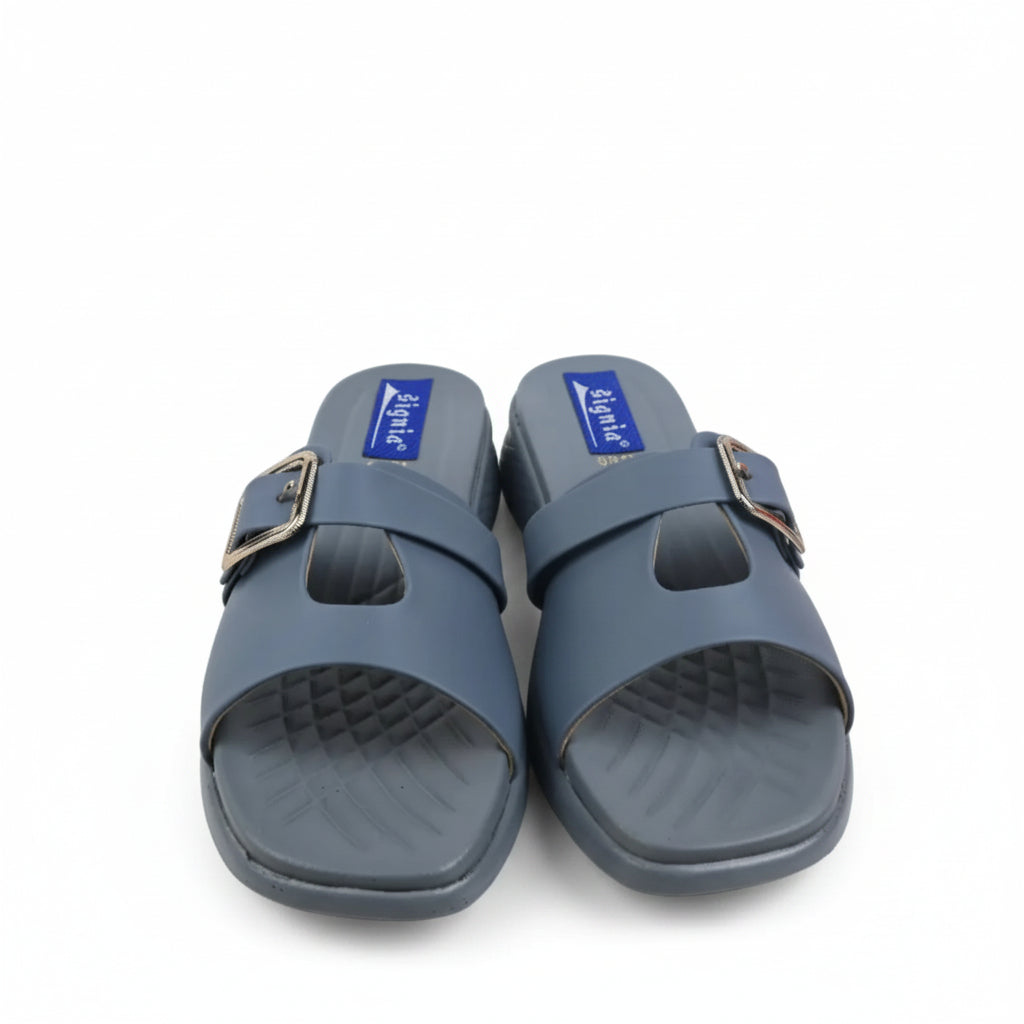 A pair of slate blue slide sandals with a single wide strap and a gold-tone buckle, shown on a white studio background.