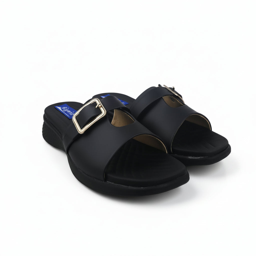 A pair of black slide sandals with a square buckle strap, displayed on a white fabric background.