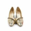 A pair of metallic gold pointed-toe high heels with a rhinestone-embellished strap across the instep, displayed on a white surface next to a red shoebox.