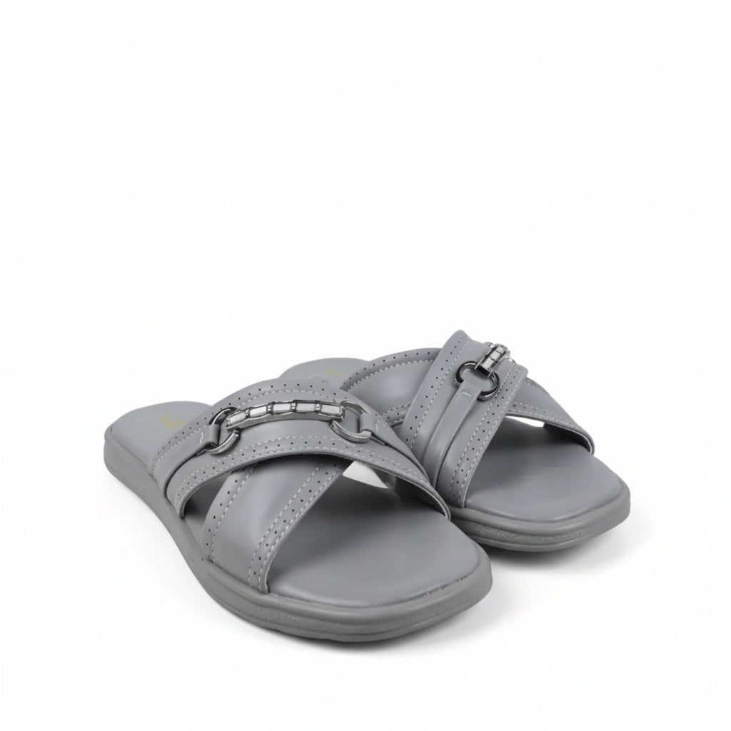 A pair of light pink slide sandals with double straps and gold-tone horsebit hardware, photographed on a white studio sweep with some visible creases and a black cable in the foreground.