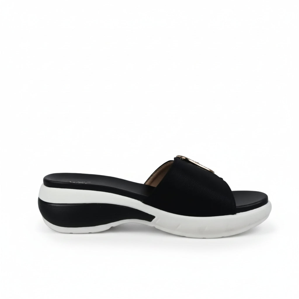 A black platform slide sandal with a chunky white sole, shown from a side profile against a white fabric backdrop.