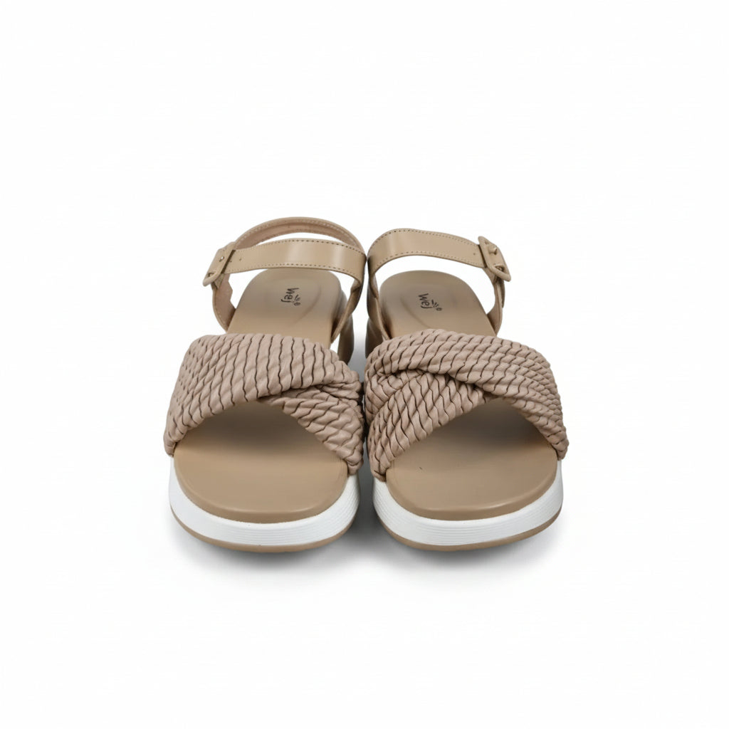 A pair of beige rope-knit flat sandals with adjustable ankle straps and white soles, displayed next to a cream-colored shoebox on a light gray fabric background.