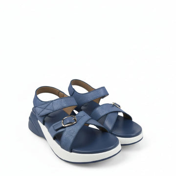 A pair of women's platform sandals in blue, featuring textured straps with silver buckle details and thick white platform soles, photographed on a light gray fabric background.