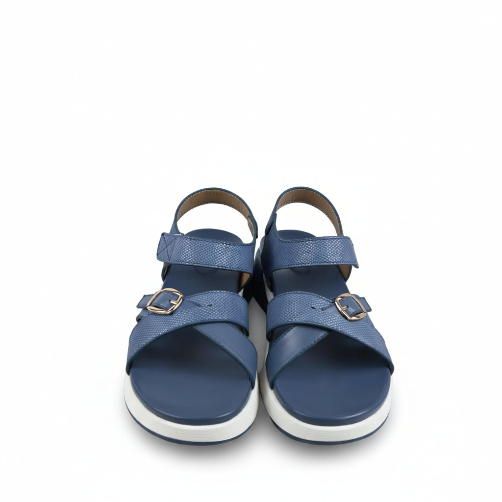 A pair of women's platform sandals in blue, featuring textured straps with silver buckle details and thick white platform soles, photographed on a light gray fabric background.