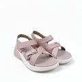A pair of women's platform sandals in light pink, featuring textured straps with gold-tone buckles and a thick white platform sole, shown against a light gray fabric backdrop.