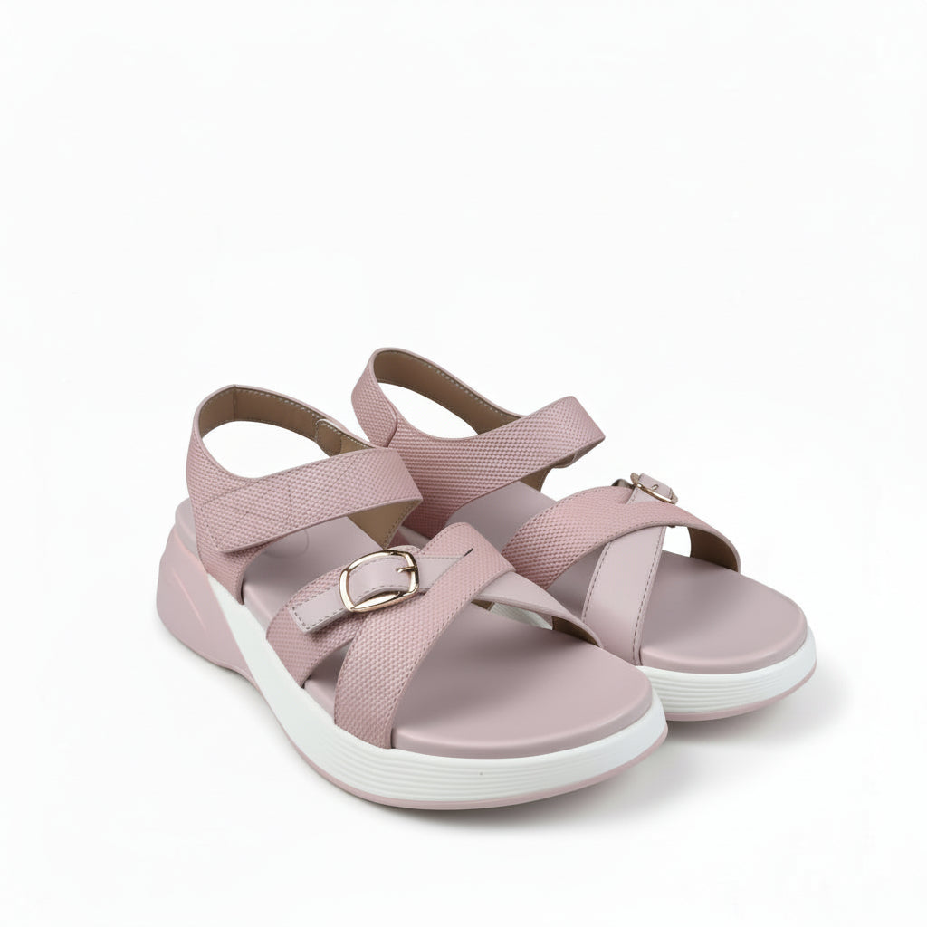 A pair of women's platform sandals in light pink, featuring textured straps with gold-tone buckles and a thick white platform sole, shown against a light gray fabric backdrop.