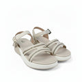 A pair of women's platform sandals in beige with metallic silver rhinestone-embellished straps, displayed on a white fabric backdrop.