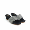 A pair of women's heeled slide sandals with wide, textured metallic silver and gold woven straps, black soles, and block heels, shown on a white studio backdrop.
