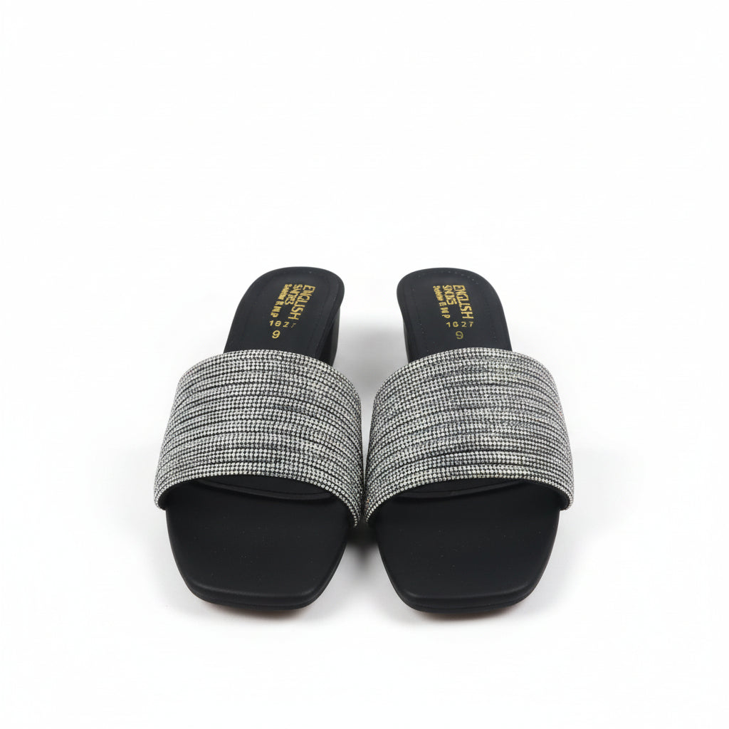 A pair of women's slide sandals with black feet and wide, textured metallic silver straps, shown next to their red and blue box on a white background.