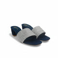 A pair of women's heeled slide sandals with textured silver woven straps and navy blue soles, photographed on a white studio sweep backdrop.