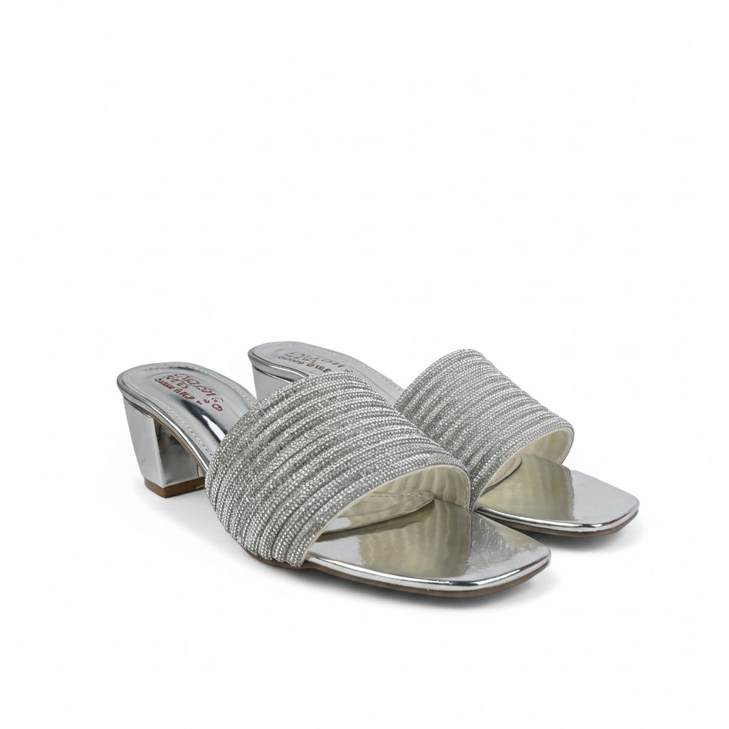 A pair of women's heeled slide sandals with textured silver woven straps and metallic silver block heels, shown on a white studio backdrop.