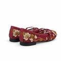 A pair of red flat shoes with white and gold floral embroidery, shown from a side-rear angle against a white studio background.